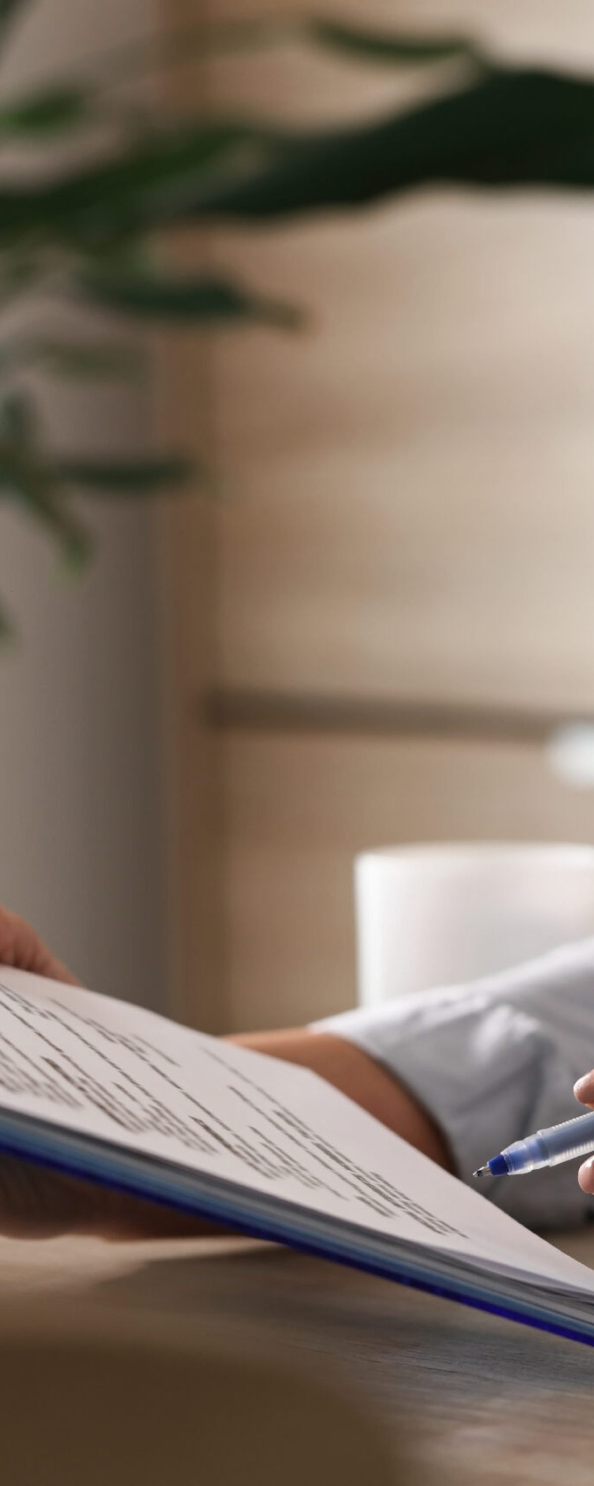 Unrecognizable female entrepreneur analyzing business reports while working on paperwork in the office.